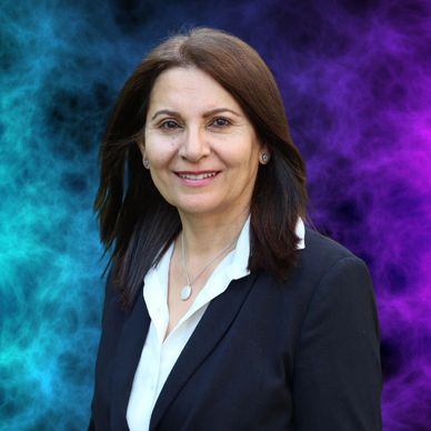 Professional woman in a dark blazer with a colorful smoky background.