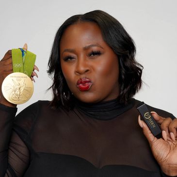 Woman proudly holds an Olympic gold medal and a lipstick product.