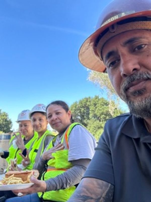 Construction workers taking a break outdoors with food and smiles.