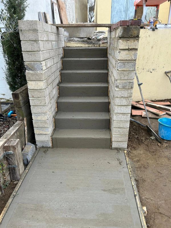 Freshly poured concrete, light brick retaining walls at a residential home entrance.