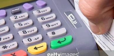 Hand swiping a card through a payment terminal's card reader.