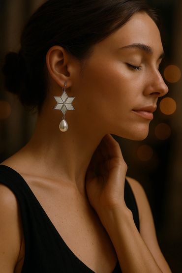 Woman with closed eyes wearing star-shaped earrings with pearl drops.