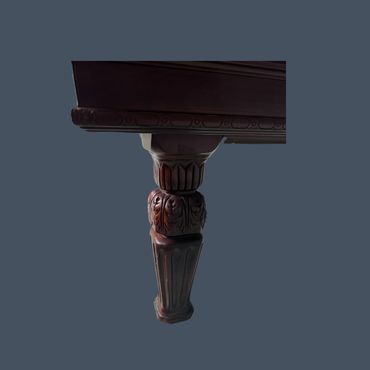 Carved wooden table leg with intricate floral and fluted designs.