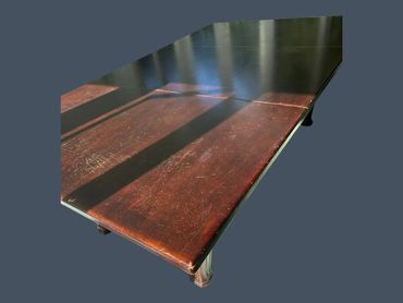 Rectangular wooden table with a worn brown and black surface.