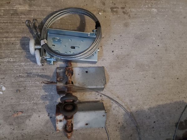 Rusted garage door cables, bottom brackets andd rollers side by side with a new set of cables