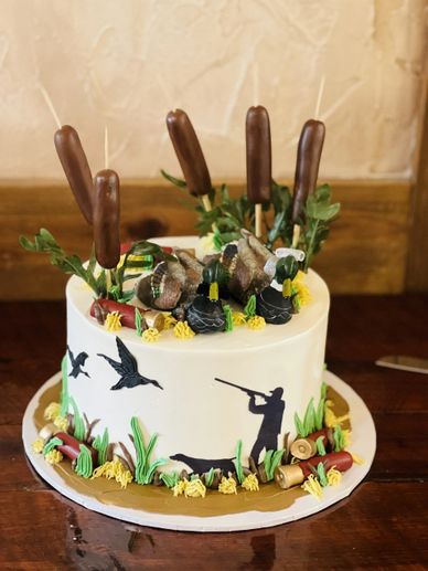 A hunting-themed cake with duck decorations and chocolate bullets.
