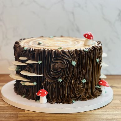 A cake designed as a tree stump with mushrooms and leaves.
