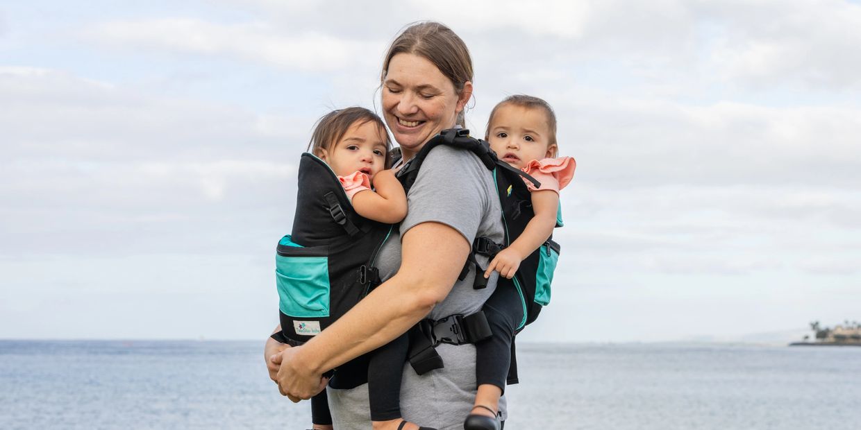 Mom wearing her twins in the Front and Back carry position enjoying getting outside