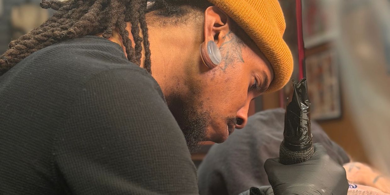 Tattoo artist focused on creating a detailed tattoo.