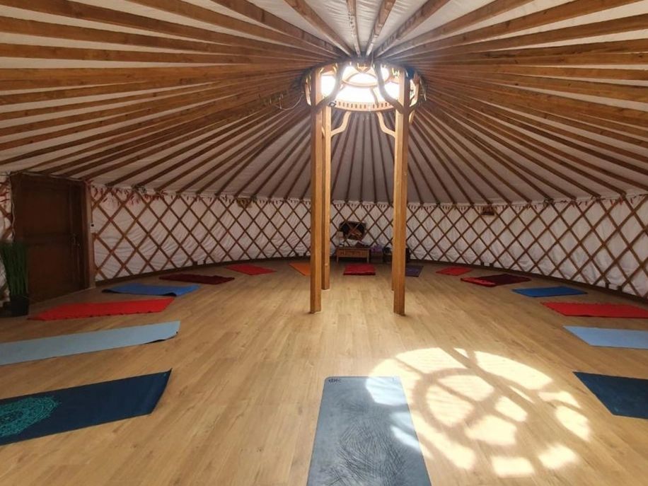 Interior of a circular yurt with yoga mats arranged around the edges.