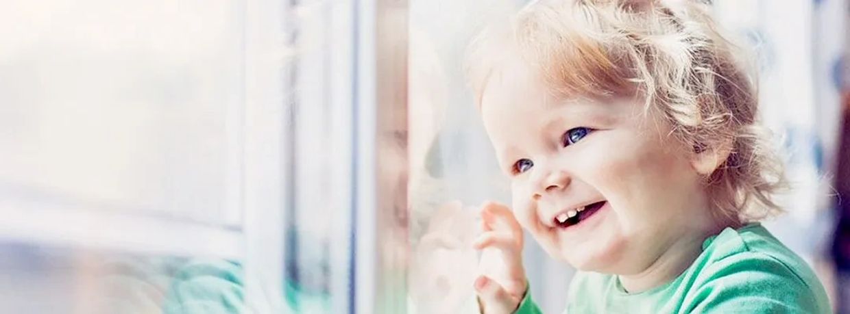 Smiling toddler looking out the window.