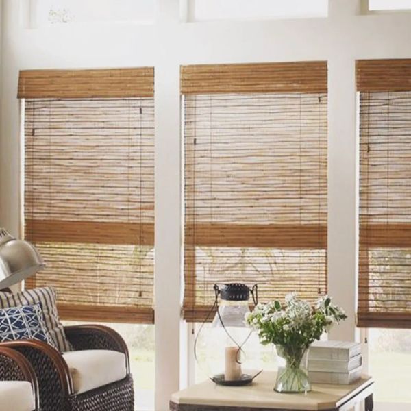 Cozy living room with bamboo blinds and wicker chair.
