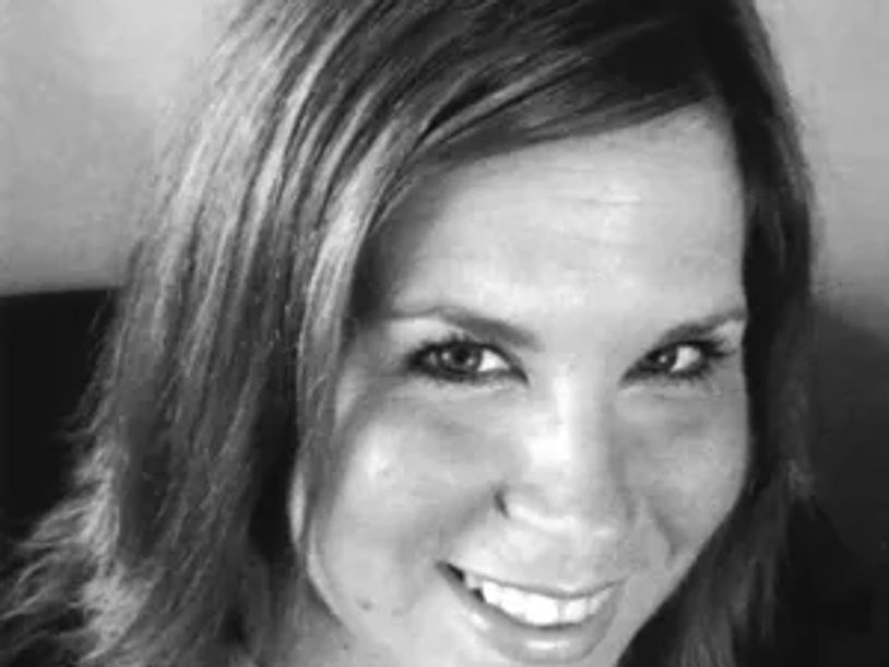 Close-up black and white photo of a smiling woman with medium-length hair.