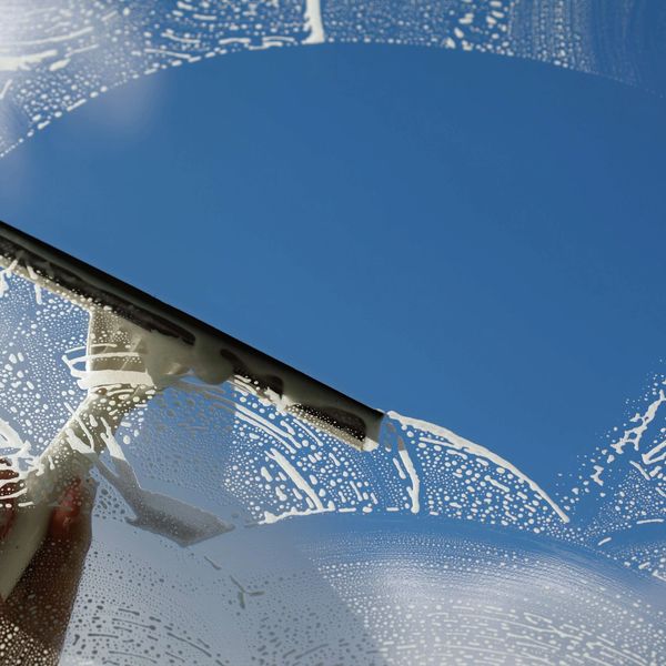 Person cleaning a window by hand with a squeegee.