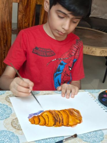 Boy painting a croissant on paper.