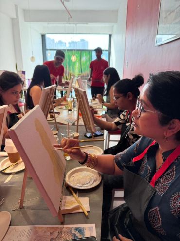 People painting on canvases in a bright room.