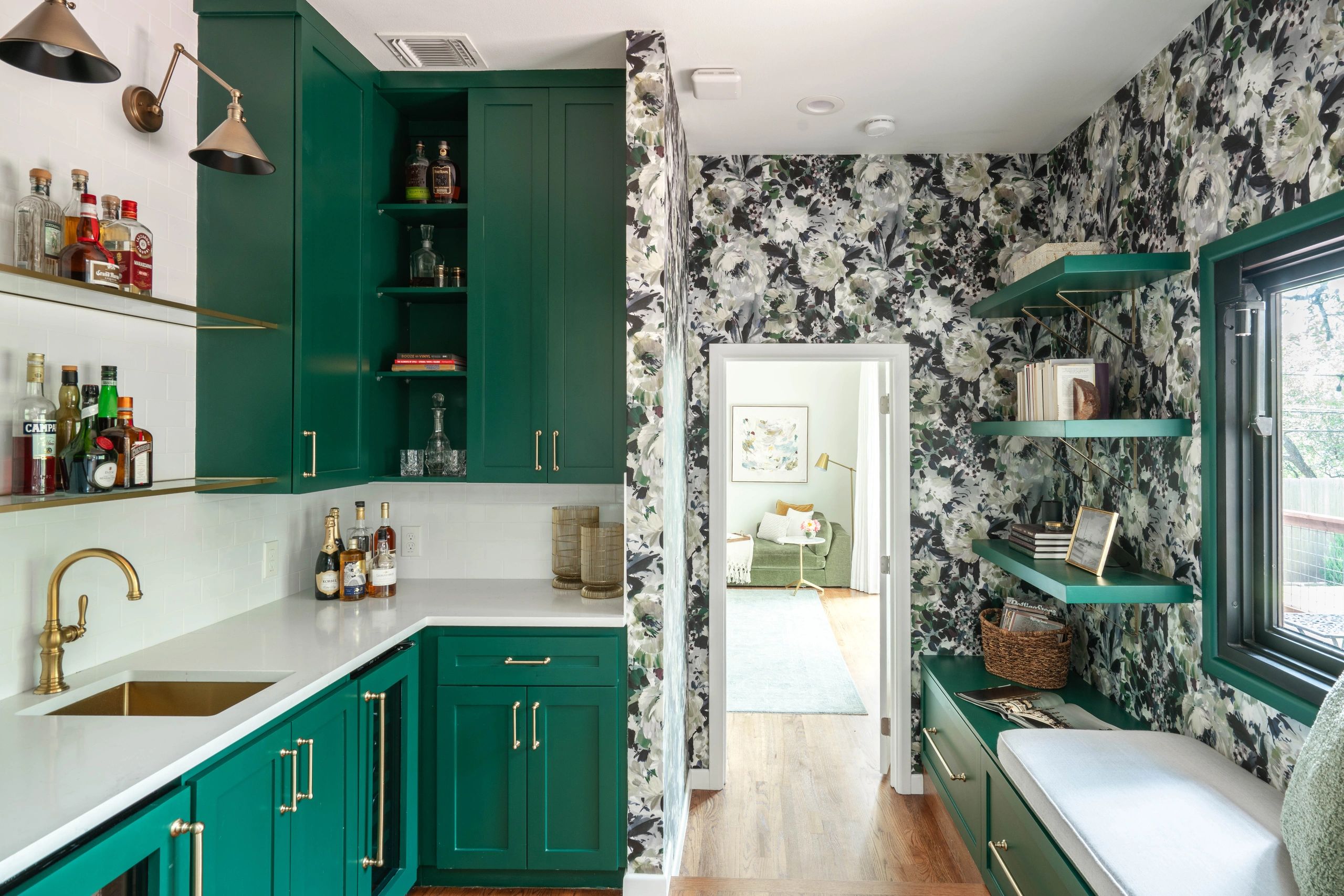 Austin, TX bar w/ emerald green cabinets, floral wallpaper, brass accents, and built-in reading nook