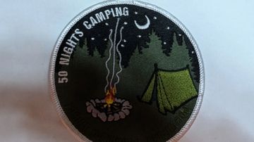 Embroidered camping patch with campfire and tent under moon and stars.