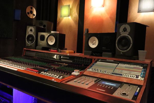 Professional audio mixing console in a recording studio with speakers and acoustic panels.