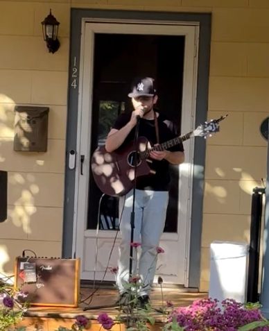 Man playing guitar and singing on a porch.