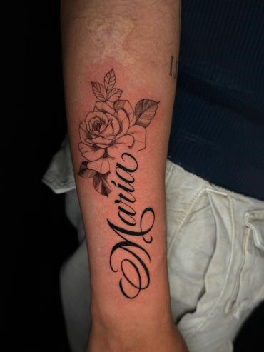 Tattoo of a rose and the name Maria on forearm.
