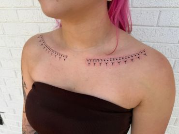Delicate dotted line tattoo across both collarbones.