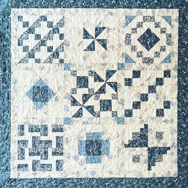 Blue and white quilt with various geometric patchwork patterns.