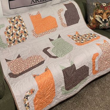 A handmade quilt with cat silhouettes in various patterns.