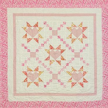 Pink and floral quilt with heart and star patterns.
