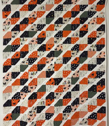 Colorful Halloween-themed quilt with black cats and orange patterns.