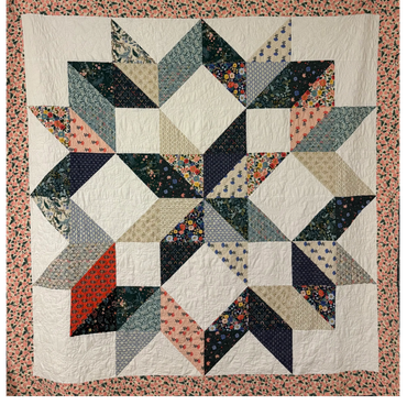Colorful geometric star quilt with floral border.