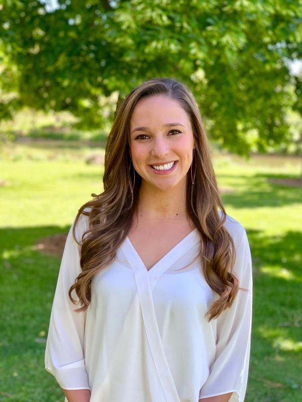 Smiling woman outdoors in a white blouse.