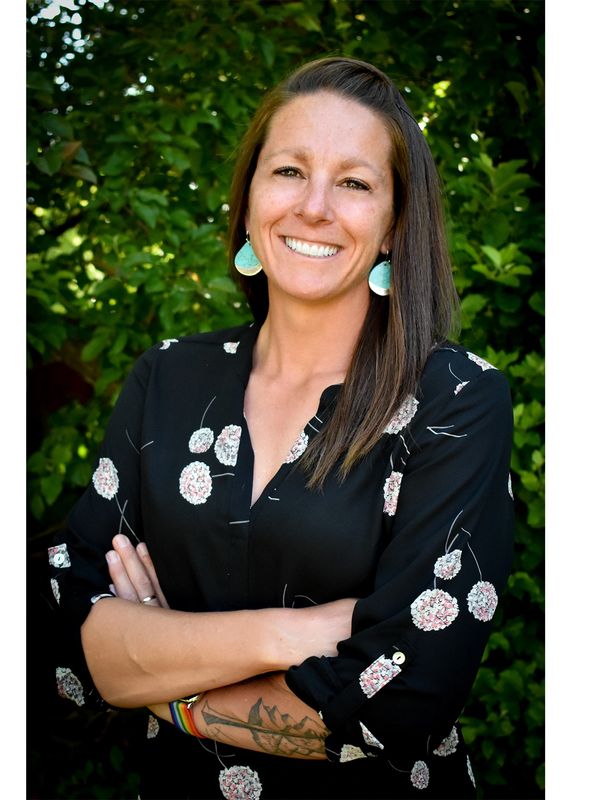 Smiling woman with floral blouse and turquoise earrings.