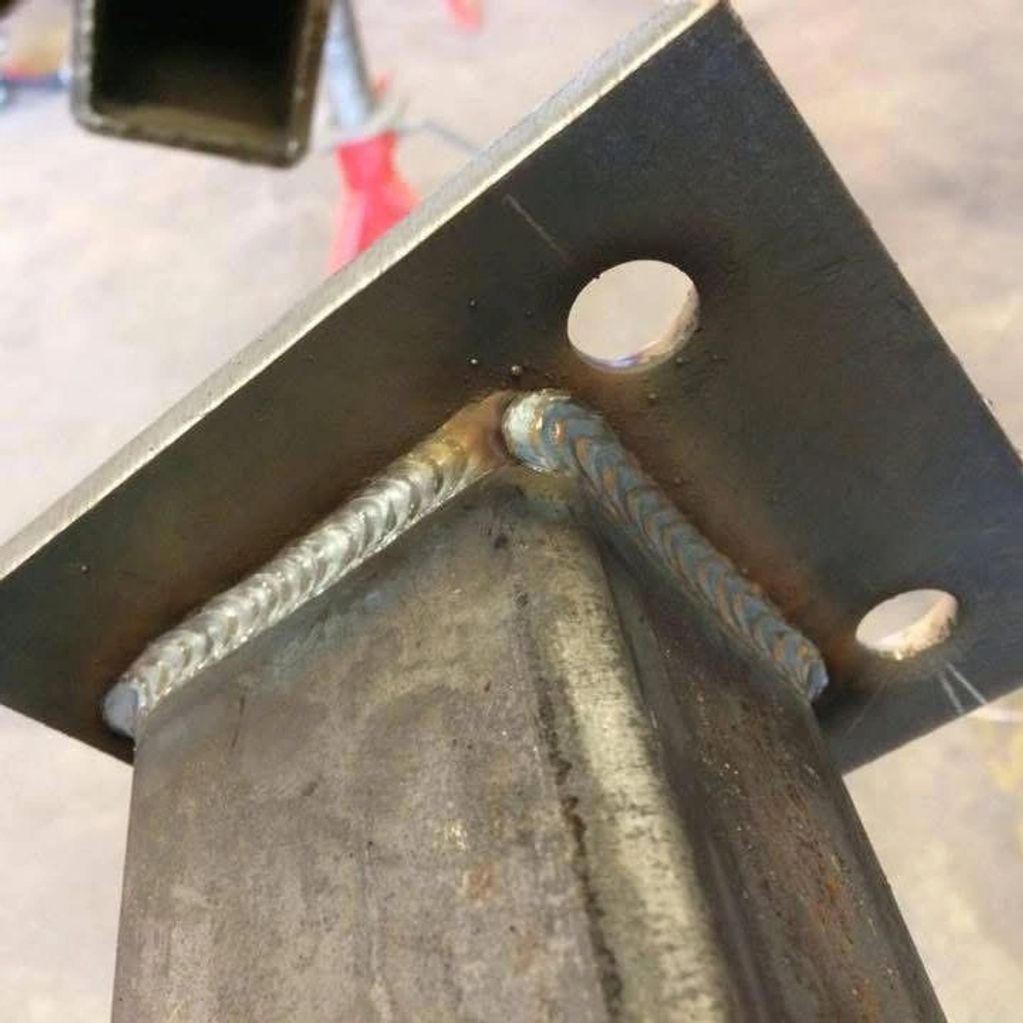 Close-up of a welded metal joint with a plate and square tubing.