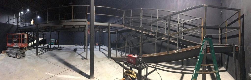 Metal framework structure under construction inside a large industrial space.