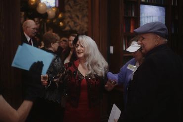 People socializing at an indoor gathering with balloons and decorations.