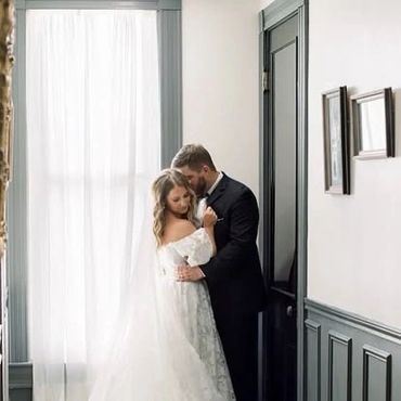 Bride and groom sharing a tender moment in a softly lit room.
