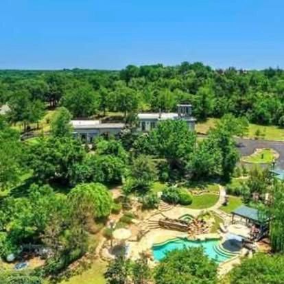Aerial view of a lush green estate with a pool and garden.