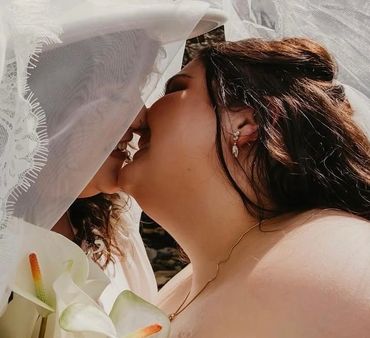 Bride and groom share a tender kiss under the veil on their wedding day.