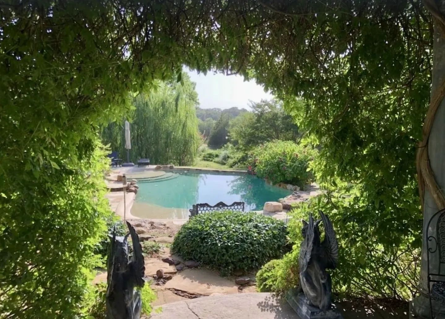 A serene garden pool framed by lush greenery and statues.
