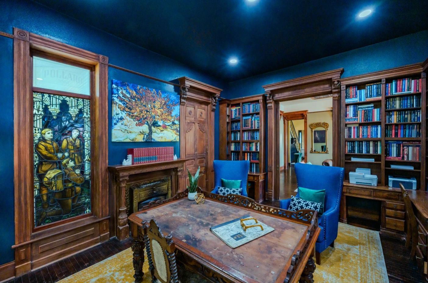 Elegant study room with blue walls, wooden bookshelves, and a vintage table.