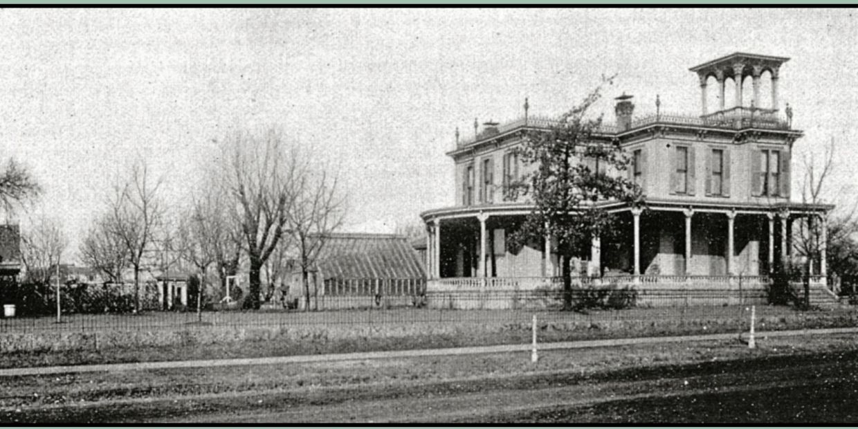 Historic large two-story house with a wraparound porch and tower.