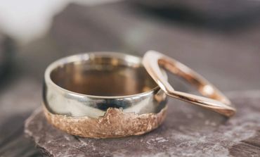 Two rings, one silver and one rose gold, on a stone surface.