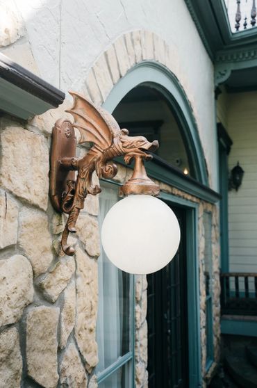 Ornate dragon-shaped wall lamp with a glowing globe on a stone exterior.