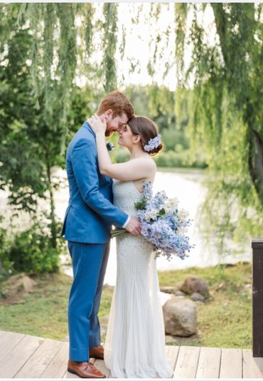 Bride and groom touching foreheads in a serene outdoor setting.