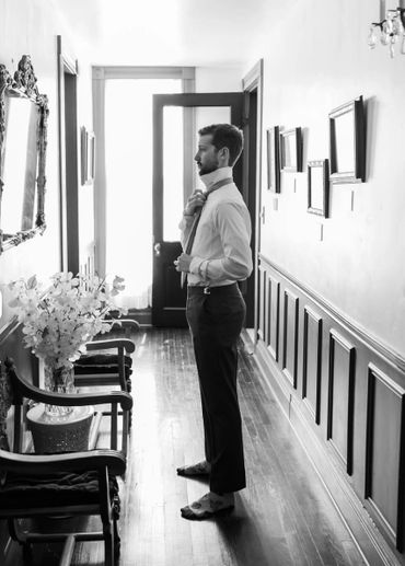 Man adjusting his tie in a vintage hallway.