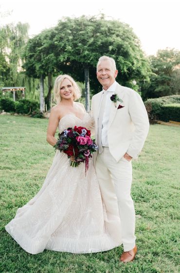 Bride and groom posing outdoors in elegant wedding attire.
