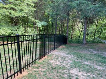 Black ornamental fence that is 4 foot tall, going through the yard and woods. 