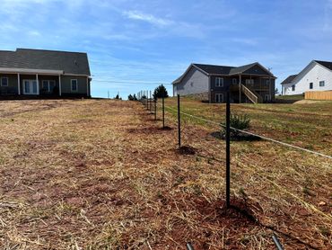 Setting black chain-link fence posts. 
