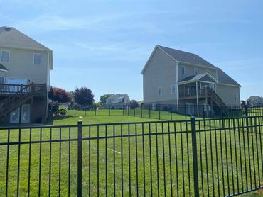 Black aluminum ornamental fence that is 54” tall, in the backyard. 